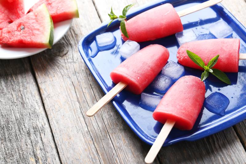 Watermelon popsicle on tray on grey wooden table